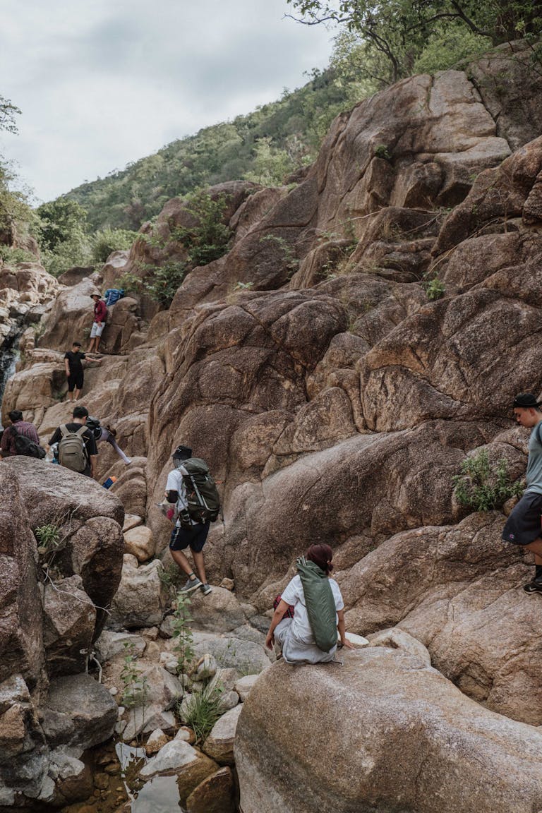 People Hiking Through Rocky Trail in Mountains